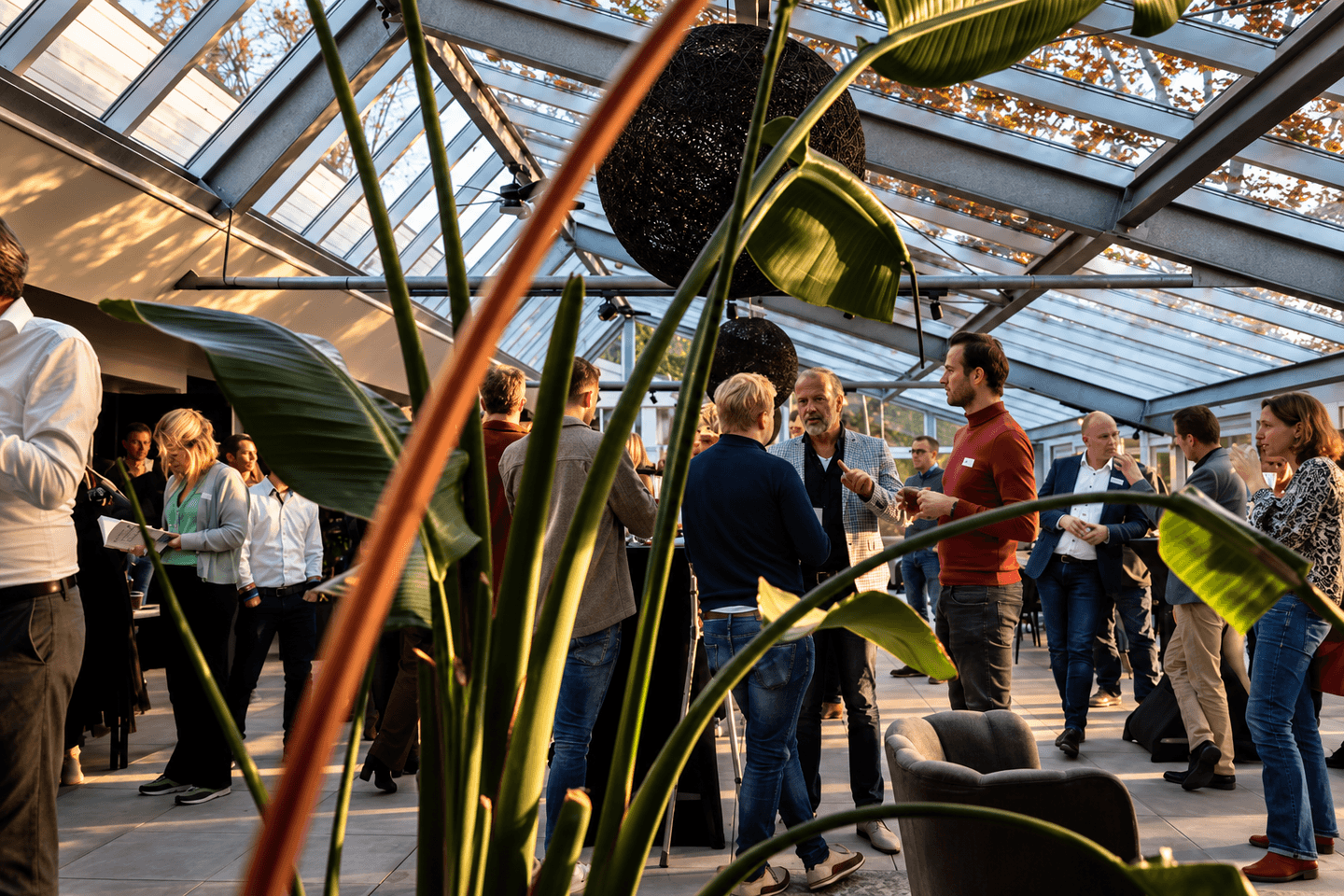Deelnemers in gesprek onder een glazen kap tijdens een bijeenkomst van Agenda voor het Hart